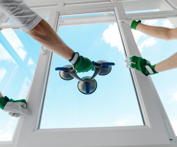 Holding glass with a vacuum lifter. Two guys installing a window in a new building. Construction site, industrial job.